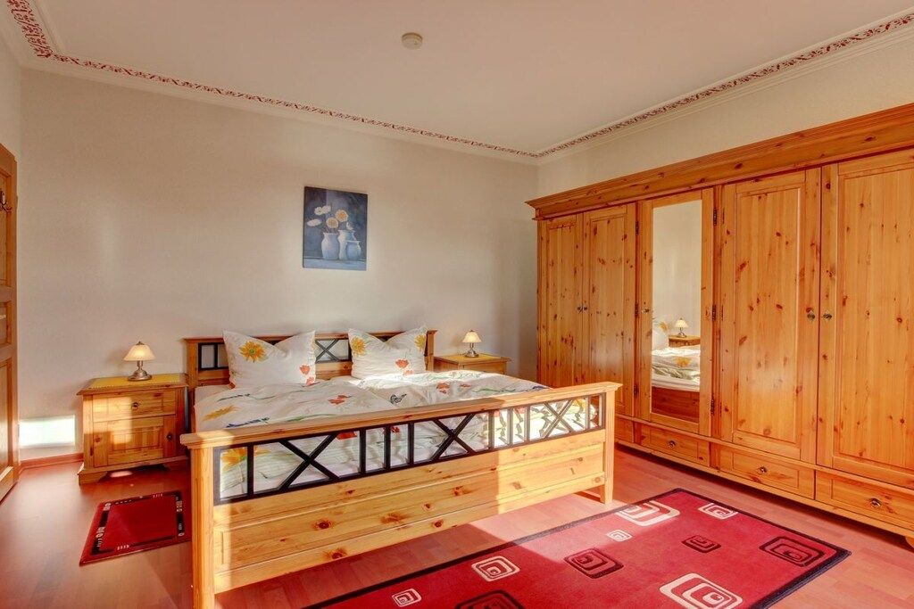 A bedroom with a wooden bed, a wardrobe, and a nightstand.