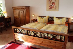 Ein Schlafzimmer mit einem Holzbett, zwei Nachttischen, einem Kleiderschrank und einem roten Teppich.