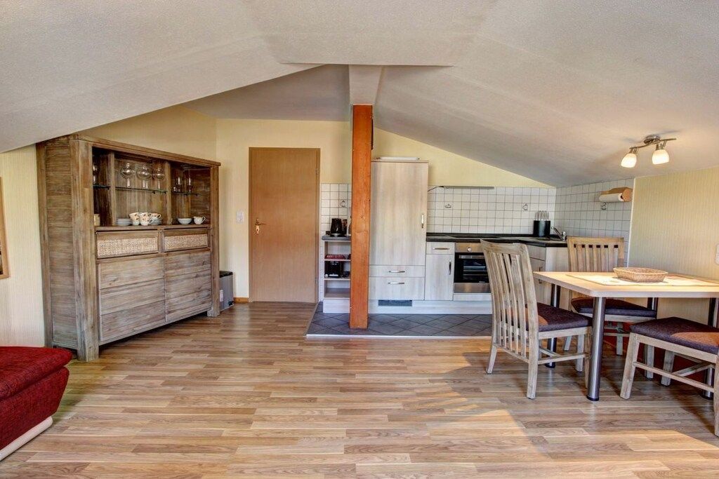 Une cuisine spacieuse avec un coin repas, des meubles en bois et un parquet disposé en motif à chevrons.