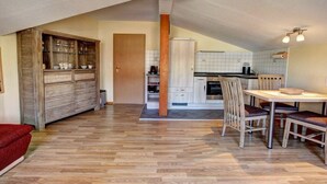 A spacious kitchen with a dining area, wooden cabinets, and a herringbone floor pattern. - Holiday apartment Donnerkeil (Sassnitz)