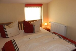 Een hotelkamer met een bed, een raam met gordijnen, een bedlamp en een radiator.