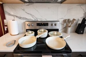 A kitchen with a stove, pots, a paper towel holder, and utensils. - Moody Designer Retreat Near Greenville & Downtown (Dallas)