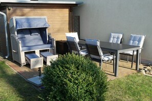 Et udendørs siddeområde med sofa, stole og et bord.