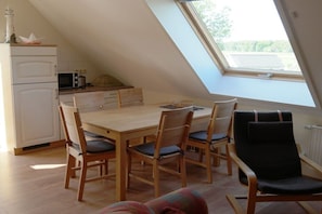 A dining area with a wooden table and chairs, a white refrigerator, and a microwave. - Holiday apartment 2 in the Strandglück house (Glowe)