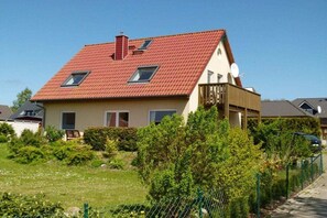 A two-story house with a red-tiled roof, a satellite dish, and a fenced yard. - Holiday apartment 2 in the Strandglück house (Glowe)