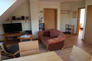 A living room with a television, a sofa, a coffee table, and a bookshelf. - Holiday apartment 2 in the Strandglück house (Glowe)