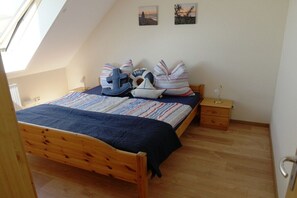 A bedroom with a sloped ceiling, a wooden bed, a nightstand, and two wall-mounted pictures. - Holiday apartment 2 in the Strandglück house (Glowe)