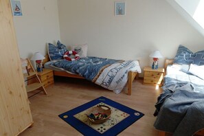 A bedroom with a bed, two nightstands, a wooden wardrobe, and a window. - Holiday apartment 2 in the Strandglück house (Glowe)