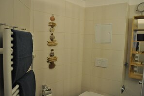 Un baño con toallero, inodoro, lavamanos y espejo.