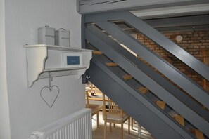 A staircase with a metal railing, a white radiator, and a shelf with containers labeled 'Coffee' and 'Sugar'. - Holiday apartment with 2 bedrooms (Kühlungsborn)