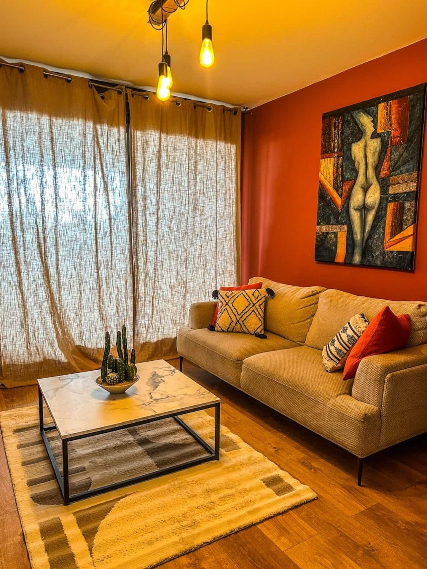 A living room with a sofa, a coffee table, a cactus plant, and a painting on the wall.