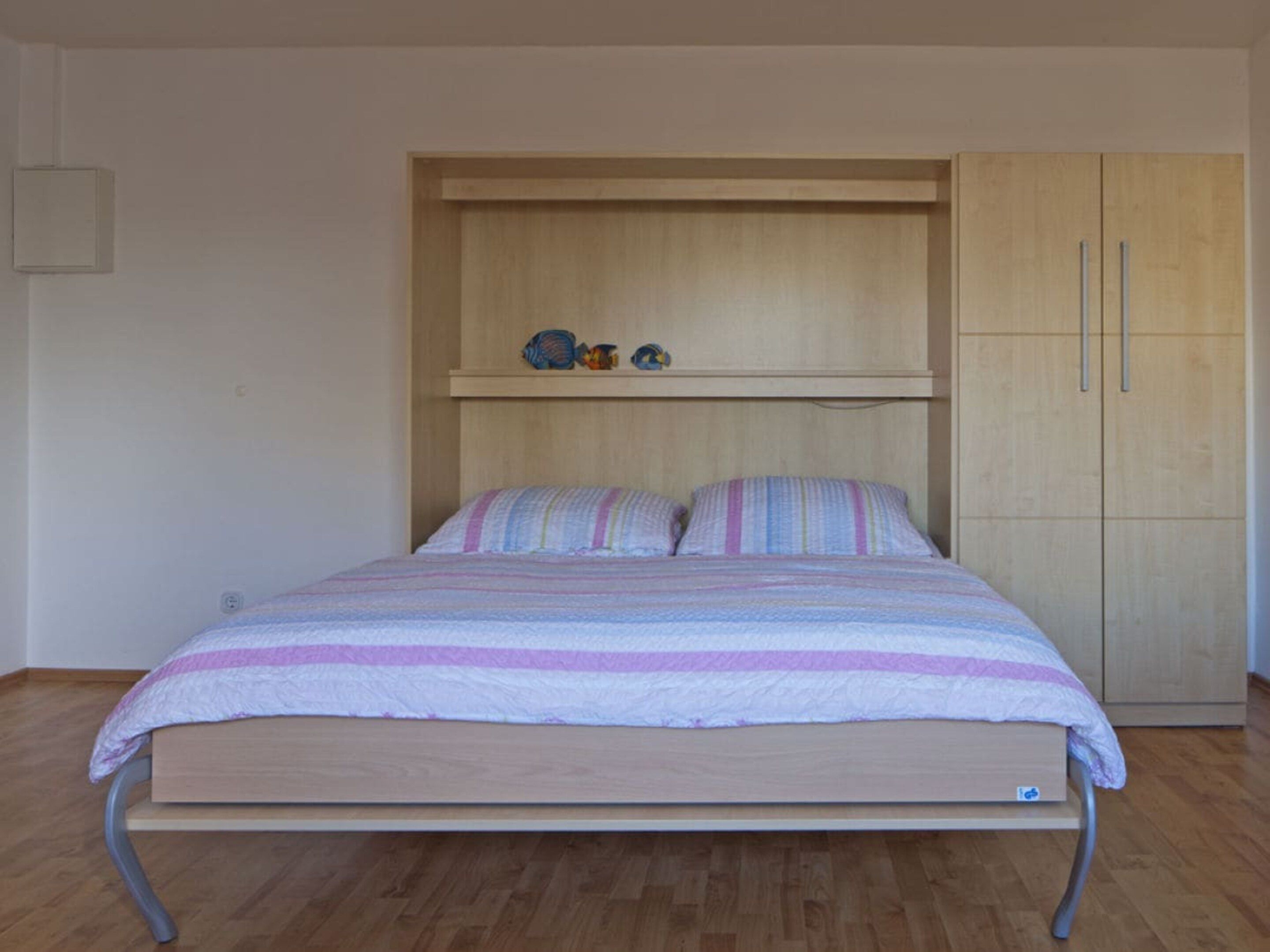 A single bed with a wooden frame and a headboard with a shelf above it.