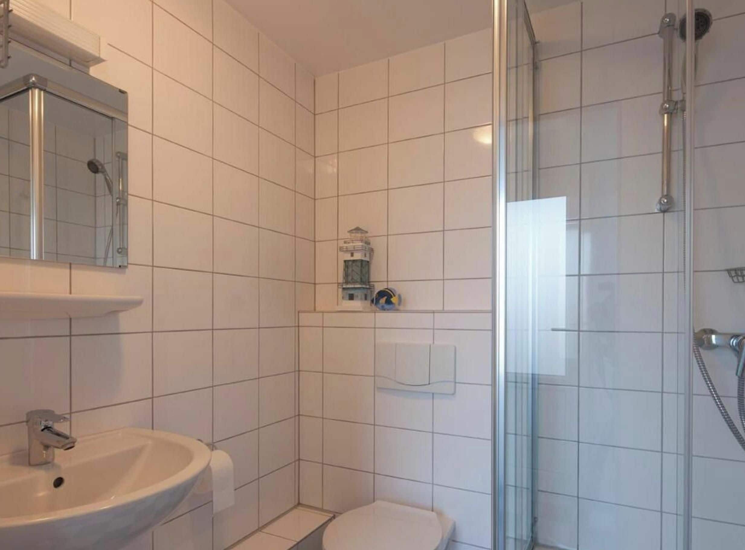 Kylpyhuone, jossa on lasiseinäinen suihkukaappi, pesuallas ja wc.