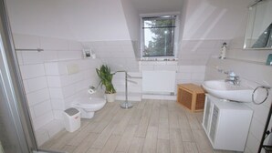 Moderni kylpyhuone, jossa on wc, bidee, pesuallas ja suihku.
