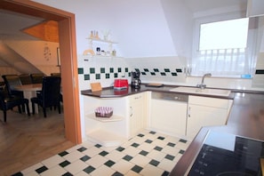 A kitchen with a checkered floor, white cabinets, a red toaster, and a window with blinds. - Holiday apartment with 4 bedrooms (Ostseeheilbad Zingst)