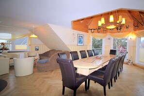 A dining area with a wooden table and chairs, a chandelier, and a staircase. - Holiday apartment with 4 bedrooms (Ostseeheilbad Zingst)