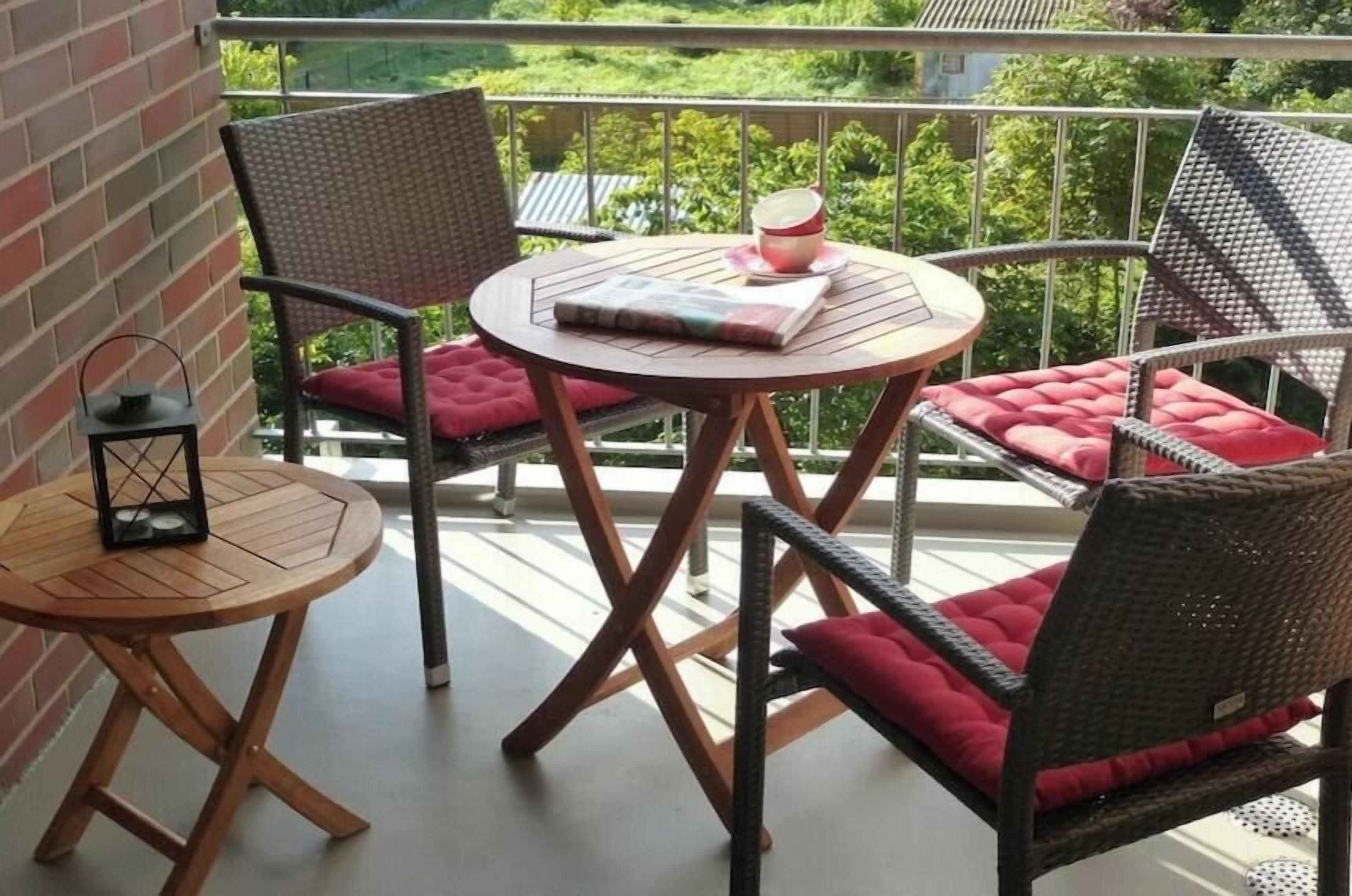 A balcony with wicker furniture, a round table, and a lantern.