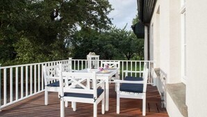 Um terraço com guarda branco, uma mesa e quatro cadeiras.