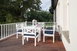 A deck with a white railing, a table, and four chairs. - Holiday home in Butzow with swimming pool (Butzow)