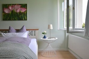A bedroom with a bed, a bedside table with a lamp, a painting on the wall, and a window. - Holiday home in Butzow with swimming pool (Butzow)