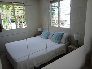 Een slaapkamer met een bed, een nachtkastje en een raam met jaloezieën.