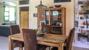 A dining area with a wooden table and chairs, a cabinet with glass doors, and a ceiling light fixture. - Vrbo Property (Sainte Anne)