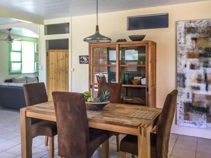 A dining area with a wooden table and chairs, a cabinet with glass doors, and a ceiling light fixture. - Vrbo Property (Sainte Anne)