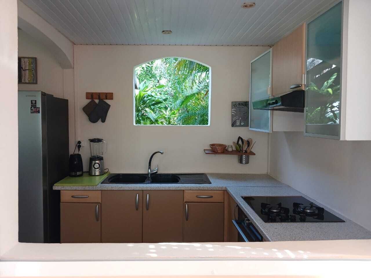 A compact kitchen with a built-in stove, a sink, and a window with a view of greenery.