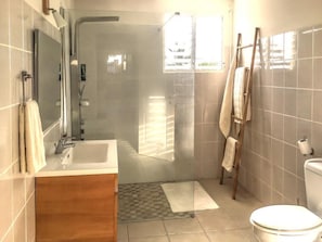 A bathroom with a shower, toilet, and sink. - Vrbo Property (Sainte Anne)