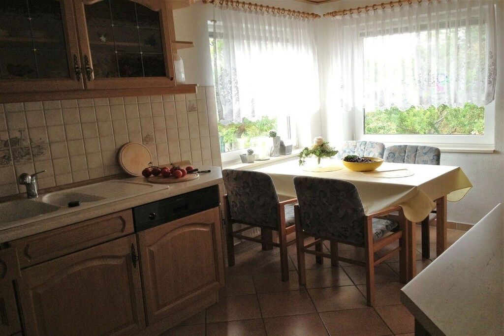 A kitchen with a dining table, chairs, and a window with curtains.