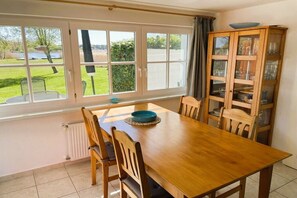 A dining area with a wooden table and chairs, a bay window with a view of the outdoors, and a cabinet with glass doors. - Holiday home in Pruchten with swimming pool (Pruchten)