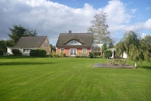A two-story house with a well-maintained lawn and a wooden deck. - Holiday home in Pruchten with swimming pool (Pruchten)
