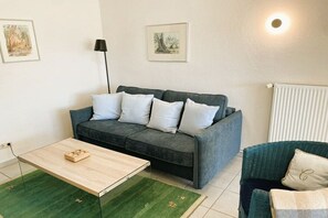 A living room with a sofa, a coffee table, a lamp, and a radiator. - Holiday home in Pruchten with swimming pool (Pruchten)