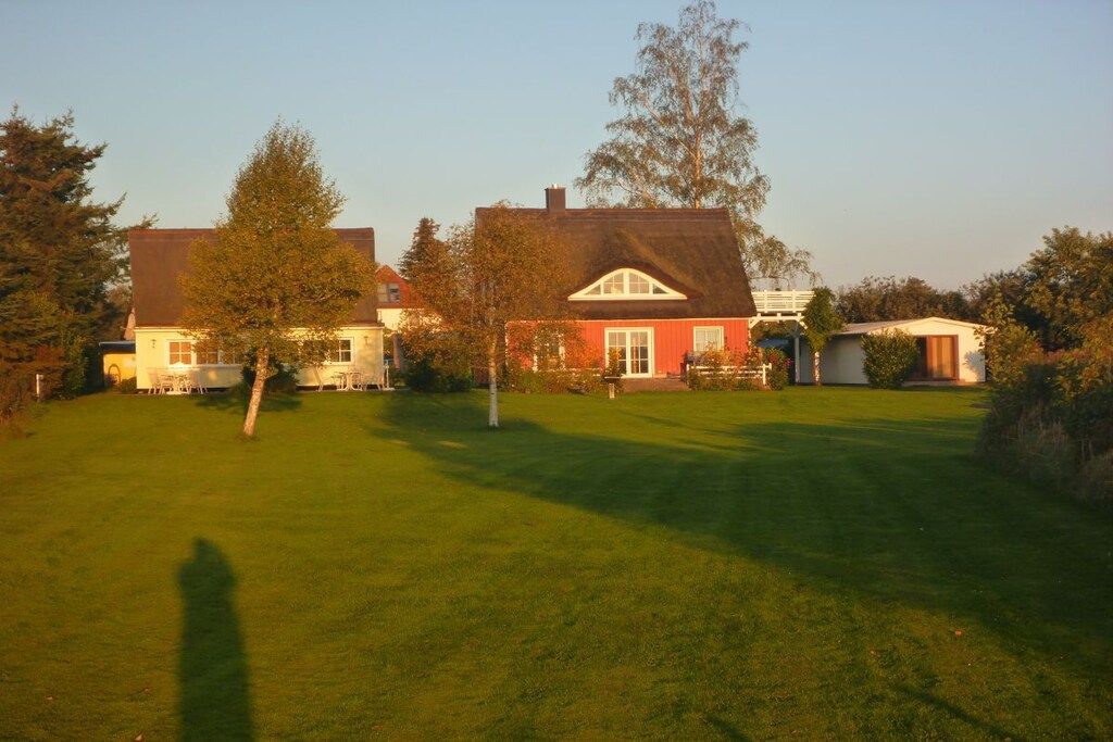 A residential property with a well-maintained lawn, a red house with a gabled roof, and a small shed in the background.