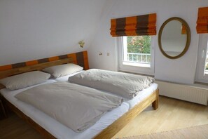 A bedroom with a double bed, a window with a view, a radiator, and a mirror on the wall. - Holiday home in Pruchten with swimming pool (Pruchten)