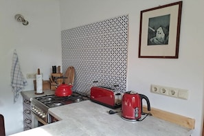Eine Küche mit Gasherd, rotem Wasserkocher, Toaster und einer ornamentierten Spritzschutzwand.