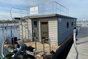 A small, single-story boat with a covered deck area, a door leading to an interior space, and a sign indicating it is a 'L'A MARE' restaurant. - Houseboat Fjord Vela (Barth)