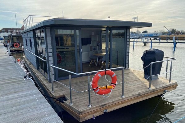 A floating structure with a covered seating area, a lifebuoy, and a grill. - Houseboat Fjord Vela (Barth)