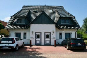 Ein zweistöckiges Gebäude mit einer symmetrischen Fassade, zwei Hauseingängen und einem Ziegeldach.