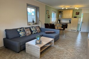 Ein modernes Wohnzimmer mit einer Couch, einem Couchtisch und Blick zur Küche.