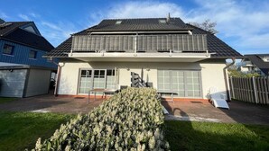A two-story house with a garage, a covered patio, and a well-maintained garden. - Holiday apartment Pahl (Ostseeheilbad Zingst)