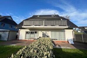 Een woonhuis met twee verdiepingen, een garage, een overdekt terras en een verzorgde tuin.