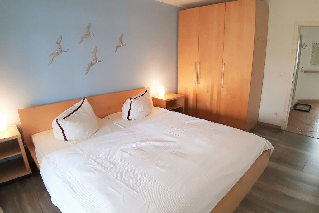 Een slaapkamer met een bed, een houten kledingkast, nachtkastjes en wanddecoratie.