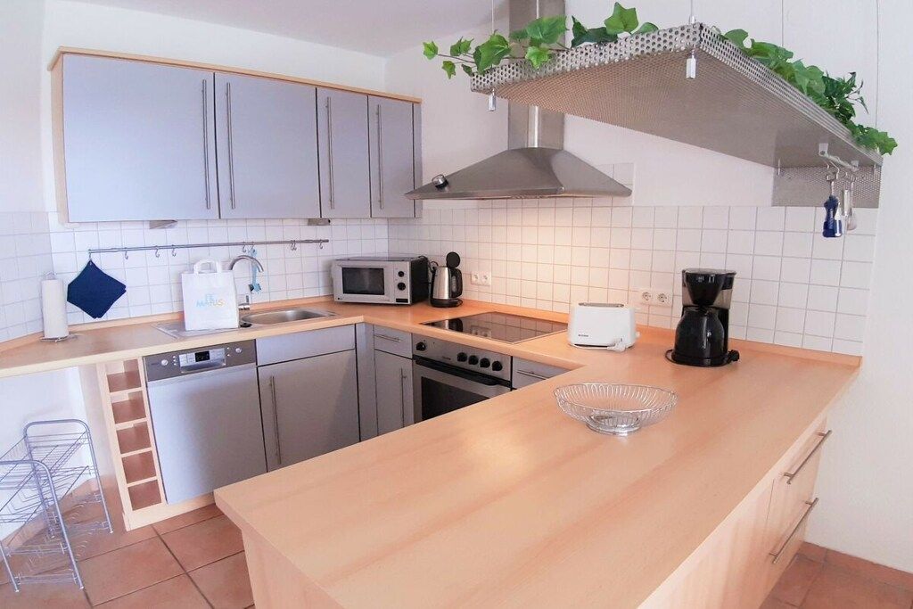 Une cuisine moderne avec des meubles gris, un four à micro-ondes, une machine à café et un lave-vaisselle.