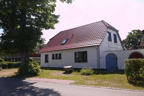 Ein eingeschossiges Haus mit rotem Ziegeldach, einer kleinen Veranda und einer blauen Tür.