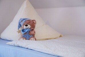 Ein Bett mit einem weißen Kopfkissen und einem Teddybär.