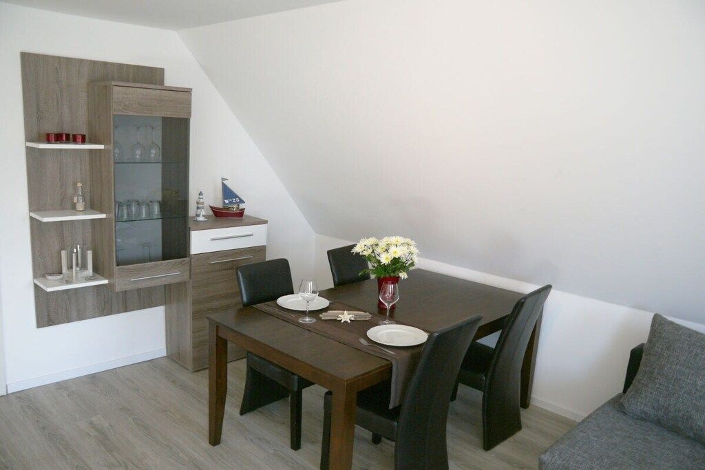Ein Essbereich mit einem dunklen Holztisch, sechs Stühlen und einer Blumenvase.