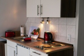 A kitchen with white cabinets, a wooden countertop, a red kettle, and a toaster. - Holiday apartment with 1 bedroom (Ostseebad Prerow)
