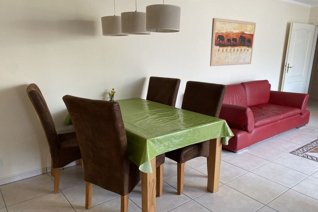 En matplats med ett bord och stolar, en röd soffa och en tavla på väggen.