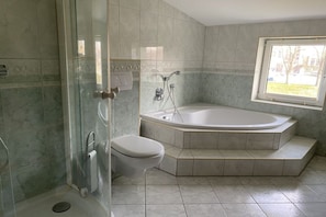 Une salle de bain dotée d’une douche à parois de verre, de toilettes séparées et d’une baignoire sur pieds.
